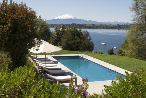 a swimming pool with lounge chairs and a mountain at Enjoy Puerto Varas in Puerto Varas