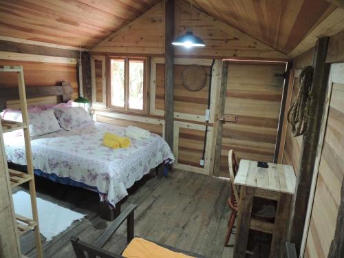 una camera da letto in una baita di tronchi con un letto e un tavolo di Paiol - Tô na Roça - Junto á natureza!!! a Cunha