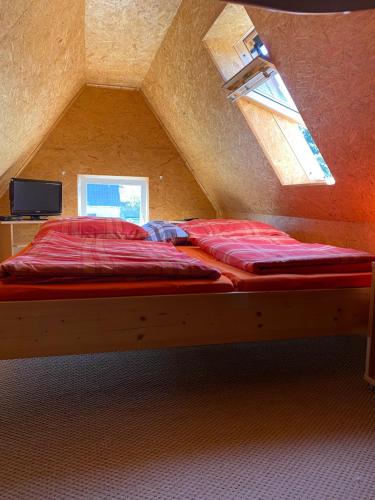 a bed with red sheets in a attic with a window at Ott‘s FEWO in Gnevsdorf