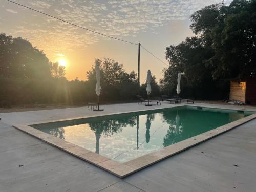 a swimming pool with a sunset in the background at Domaine de Selhac in Frontignan