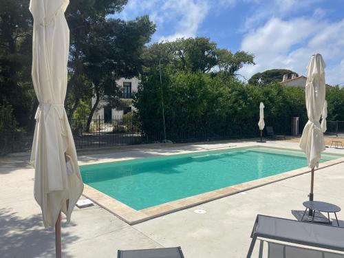 a swimming pool with two white umbrellas next to it at Domaine de Selhac in Frontignan