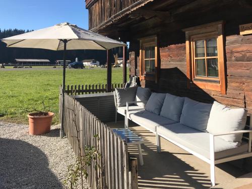 two white couches on a porch with an umbrella at The Farm in Westendorf
