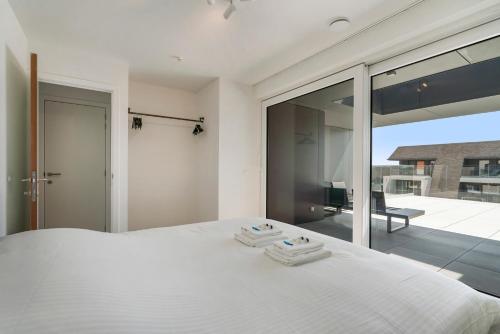 a bedroom with a white bed and a balcony at Appartement Villa Creole Jachthaven Nieuwpoort in Nieuwpoort