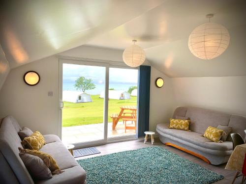 a living room with a couch and a sliding glass door at Glamping at Shieling Holidays Mull in Craignure