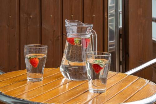 three glasses of water and a pitcher with strawberries in it at Apartamenty PIAMOLA Willa Turkusowa in Kąty Rybackie