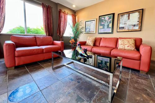 a living room with two red couches and a glass table at Court Plaza Inn & Suites of Mackinaw in Mackinaw City
