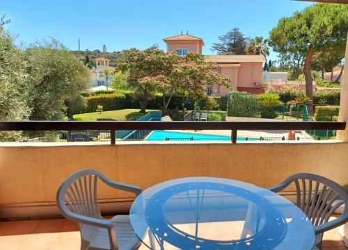 une table bleue et des chaises sur un balcon avec piscine dans l'établissement Exclusive 80 sqm apartment with private garden and terrace on the Cap d Antibes, 300 mt from sandy Plage de la Salis, à Antibes
