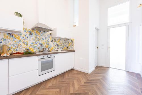 a kitchen with white cabinets and a wooden floor at Lux Aurea in Meta