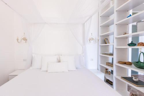 a white bedroom with a bed with white shelves at Lux Aurea in Meta