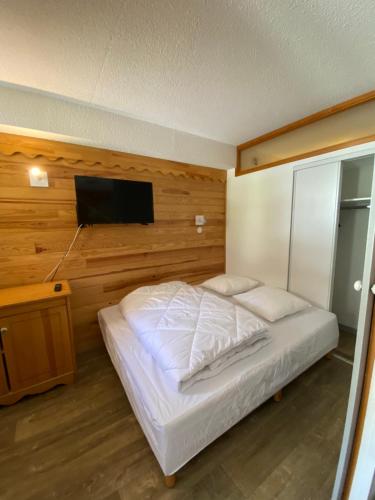 Un dormitorio con una cama y un televisor de pantalla plana. en Valmeinier 1800 - Ecrin des neiges, en Valmeinier