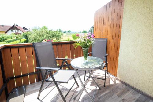 a table and chairs on a balcony with a vase of flowers at Apartment & Room Pristov in Žirovnica