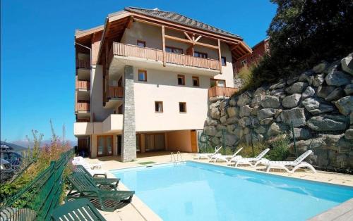 un immeuble avec une piscine devant un immeuble dans l'établissement Valmeinier 1800 - Ecrin des neiges, à Valmeinier