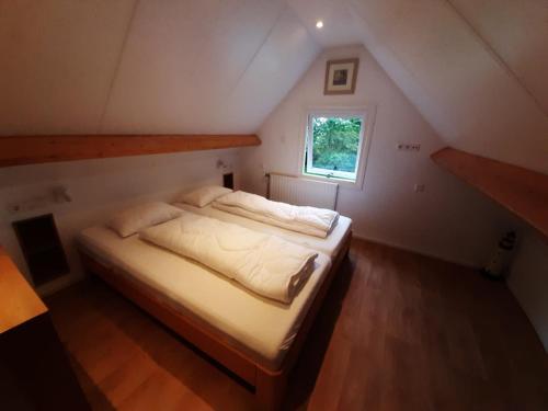 a small bedroom with a bed in a attic at Vakantiehuis Boomgaard in Vrouwenpolder