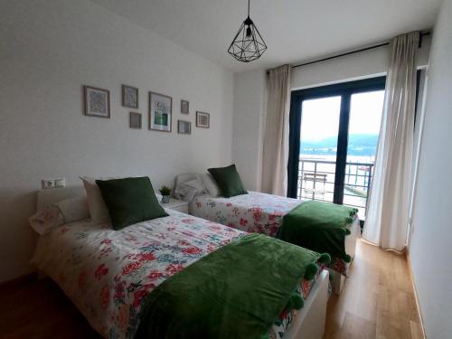 1 dormitorio con 2 camas y ventana grande en Apartamento con balcón y vistas al mar en Viveiro