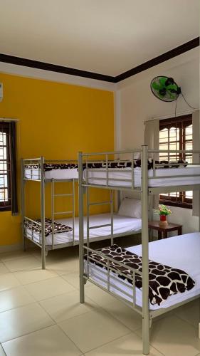 three bunk beds in a room with yellow walls at Cheerful Hoi An Hostel in Hoi An