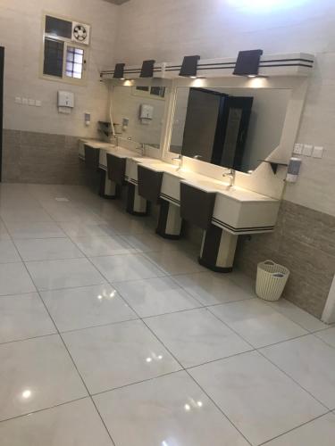 Baño con una fila de lavabos y espejos en استراحة الذروة en Abha
