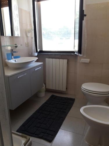 a bathroom with a sink and a toilet and a window at La Locanda Di Perico Paola in Veruno