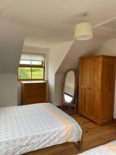 1 dormitorio con cama, tocador y espejo en Ballyloskey Road, en Carndonagh