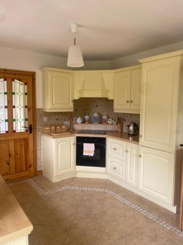 a kitchen with white cabinets and a stove top oven at Ballyloskey Road in Carndonagh