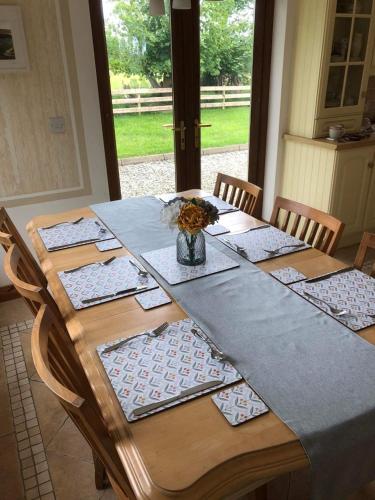a wooden table with a vase of flowers on it at Ballyloskey Road in Carndonagh