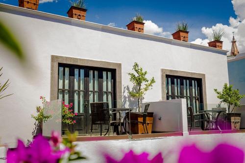 a white building with tables and chairs on a patio at Hotel Boutique Hacienda Guadalupe in San Miguel de Allende