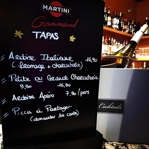 a sign with a bottle of wine in a bar at Hôtel la Scala in Pithiviers