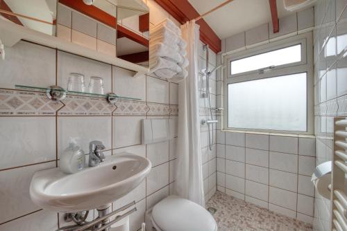 a bathroom with a sink and a toilet and a window at Hotel Pension 't Huys Grol in Renesse
