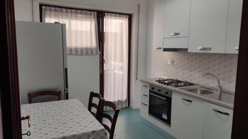 Una cocina con una mesa, un fregadero y una estufa. en Lucia House mare Nettuno, en Nettuno