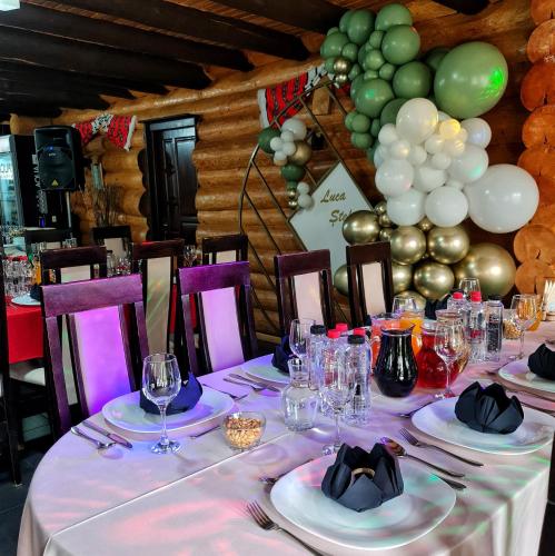 a table with plates and wine glasses and balloons at Pensiunea Agroturistica Casa Brazilor 