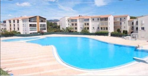 une grande piscine en face de deux immeubles d'appartements dans l'établissement appartement au LAGON BLEU à Fréjus, garage, tennis & piscine 1200 M2, à Fréjus