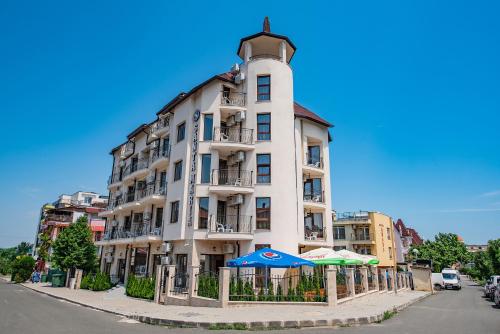 a tall white building with umbrellas in front of it at Hotel Santa Maria in Obzor
