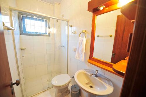 a bathroom with a sink and a toilet and a mirror at Capão Praia Hotel in Capão da Canoa