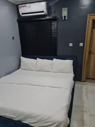 a bedroom with a bed with white sheets and a tv at Wine House, Maitama, Abuja in Abuja