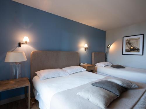 2 letti in una camera con pareti blu di Hotel Santa Maria a Saint-Florent
