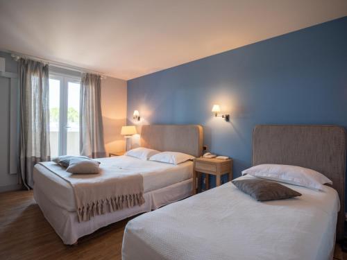 2 letti in una camera d'albergo con pareti blu di Hotel Santa Maria a Saint-Florent