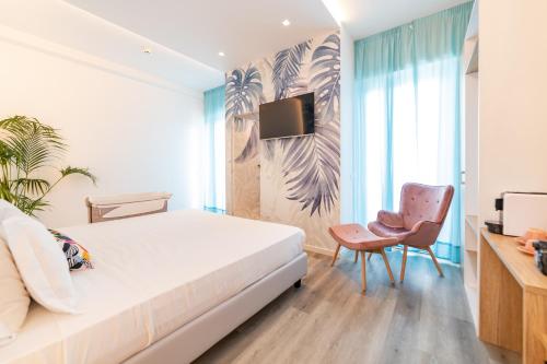 a bedroom with a bed and a chair and a tv at Hotel Majorca in Gabicce Mare