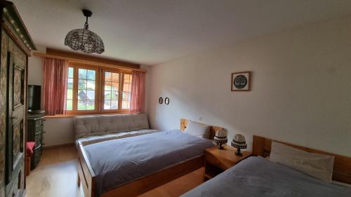 1 dormitorio con 2 camas y sofá en Snow+Surf B&B en Lauenen