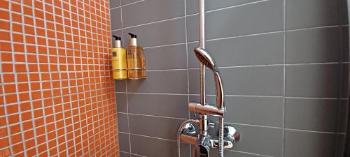 a shower in a bathroom with orange and gray tiles at The Sunset Hideout in Lisbon