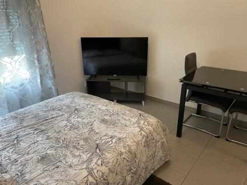 a bedroom with a bed and a desk and a television at Studio 005 in Mantes-la-Jolie