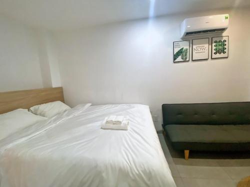 a bedroom with a white bed and a green couch at Arista in Ho Chi Minh City