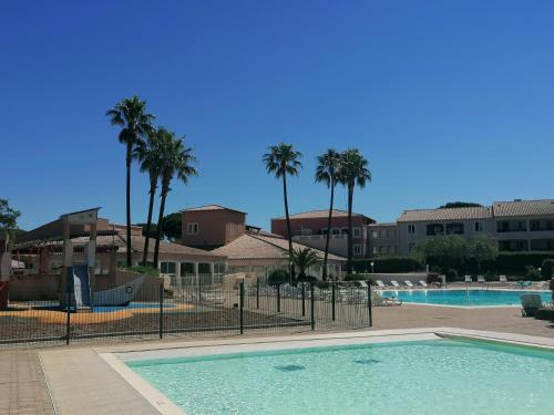 - une piscine dans un complexe avec des palmiers dans l'établissement Résidence Golfs de Valescure 9, à Saint-Raphaël