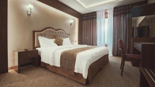 ein Hotelzimmer mit einem großen Bett und einem Schreibtisch in der Unterkunft Al-Borg Hotel in Dschāzān