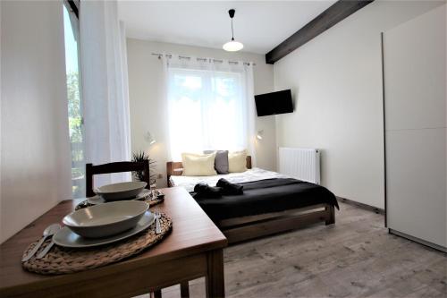 a bedroom with a bed and a table with bowls on it at Apart Studio Rambiert in Swarzewo