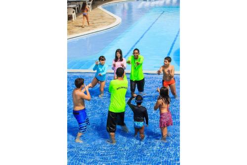 a group of people standing around a swimming pool at Flat Luxo no Villa Hípica em Gravata - PE - LocarHouse in Gravatá