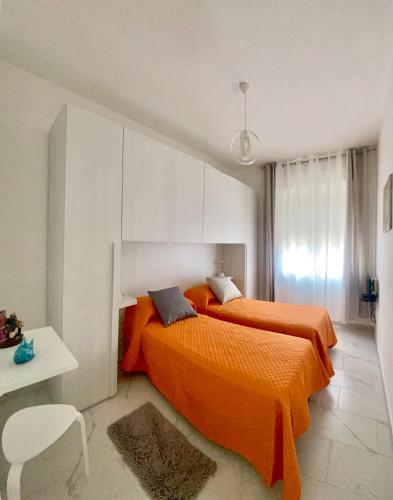 a bedroom with two beds with orange sheets and a table at Casa Tortora in Santa Maria di Castellabate