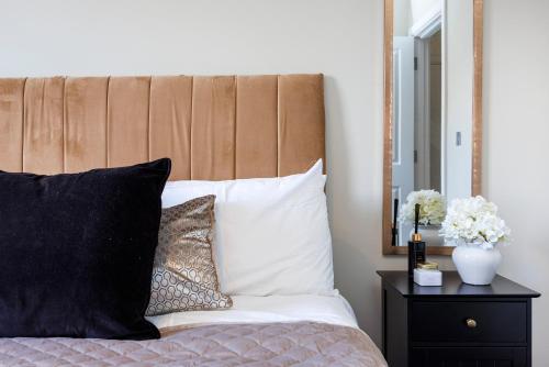 a bed with black and white pillows and a mirror at Stylish & Modern 1BR City Centre Nr the beach, High St & Adventure Island by Luxiety Stays in Southend-on-Sea