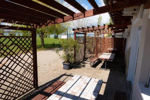a patio with two benches under a wooden pergola at Pelso Apartman in Zamárdi