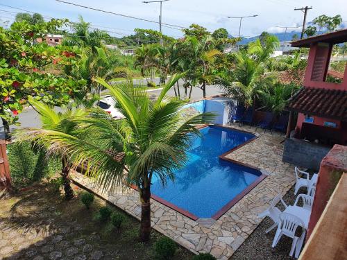 a swimming pool with a palm tree next to a house at Pousada Retiro das Caravelas in Cananéia