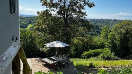 una mesa y una sombrilla en una terraza de madera en Cascina GianTino G A Y - ONLY suite Sughero en Montegrosso dʼAsti