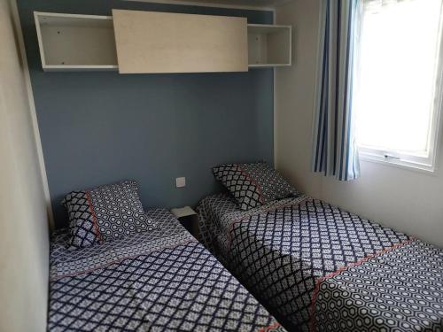 2 Betten in einem kleinen Zimmer neben einem Fenster in der Unterkunft Ma pause Charentaise in Les Mathes